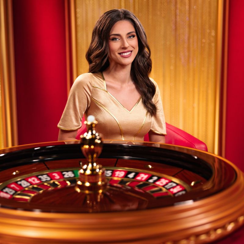 The host sat by a roulette table. This is the cover photo for Immersive Roulette Deluxe.