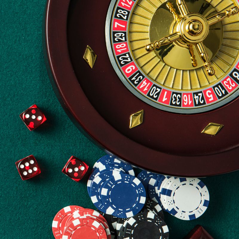 A roulette table with spinning wheel, playing cards, and dice, illustrating a Beginner's Guide to Roulette Betting Strategy.