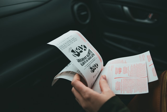 A photo of a person holding multiple lottery tickets in their hand.