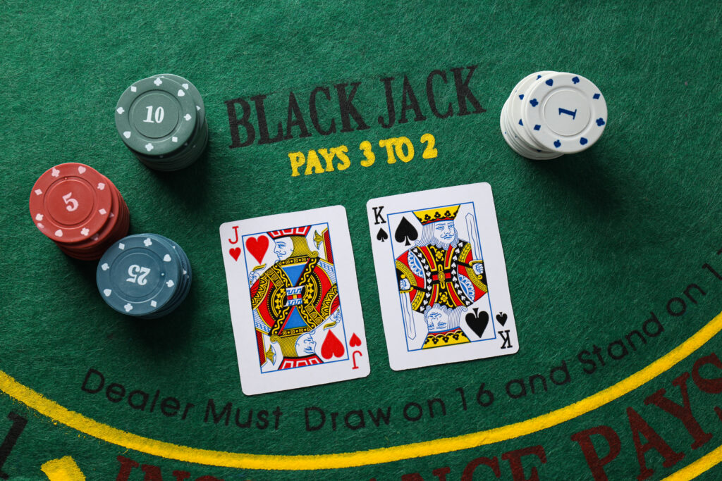 A photo of two face cards and four stacks of casino chips on a blackjack table.