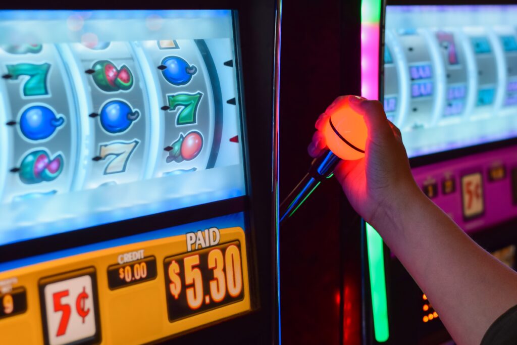 A photo of a person playing a slot machine with symbols displayed on the screen.