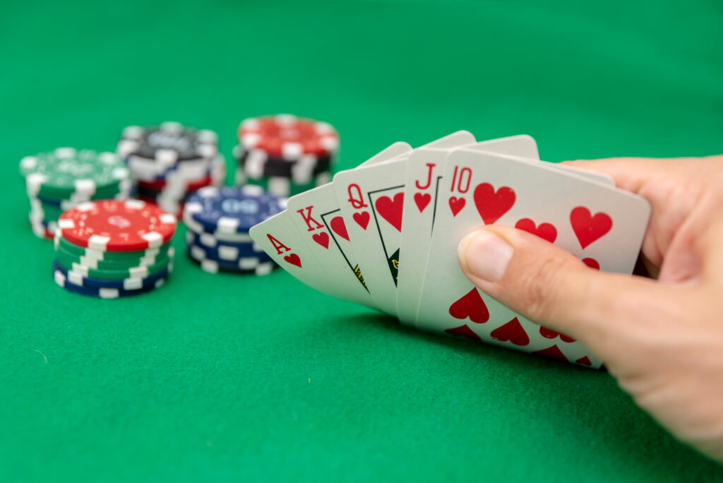 A photo of a hand holding playing cards with casino chips in the background.
