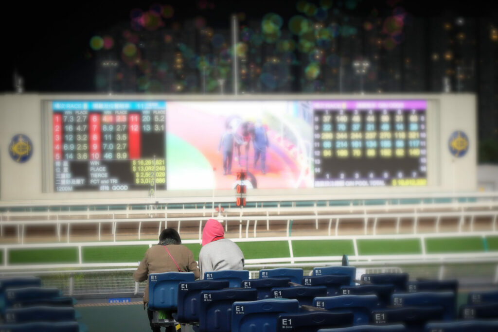 A photo of two spectators watching statistics at the horse racing.