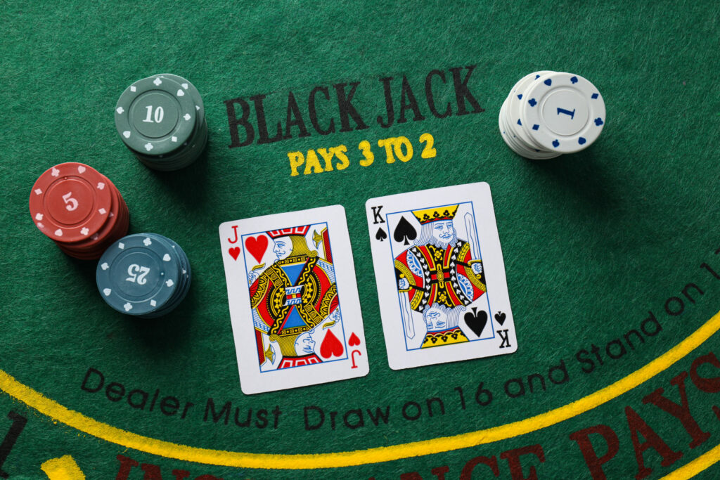 A photo of two playing cards next to casino chips on a blackjack table.