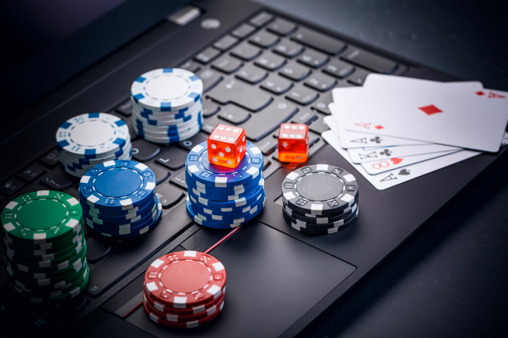 A photo of playing cards, casino chips and dice on top of a laptop keyboard.