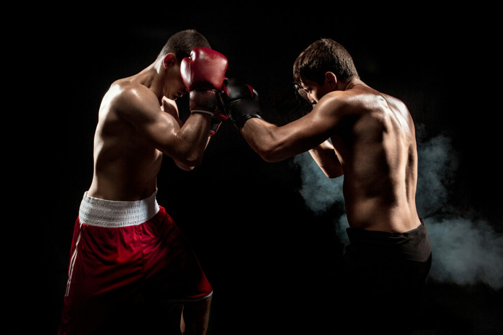 Two professional boxer boxing on black smoky studio background.