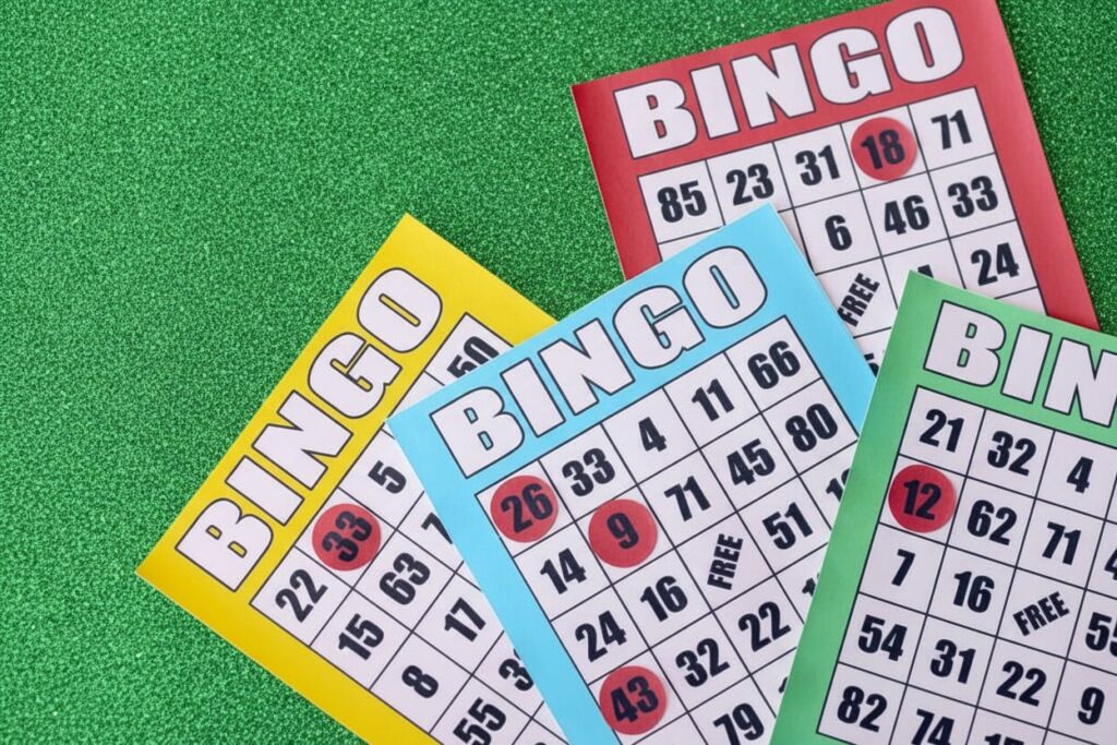 Four bingo cards with some numbers marked in red on a green background.