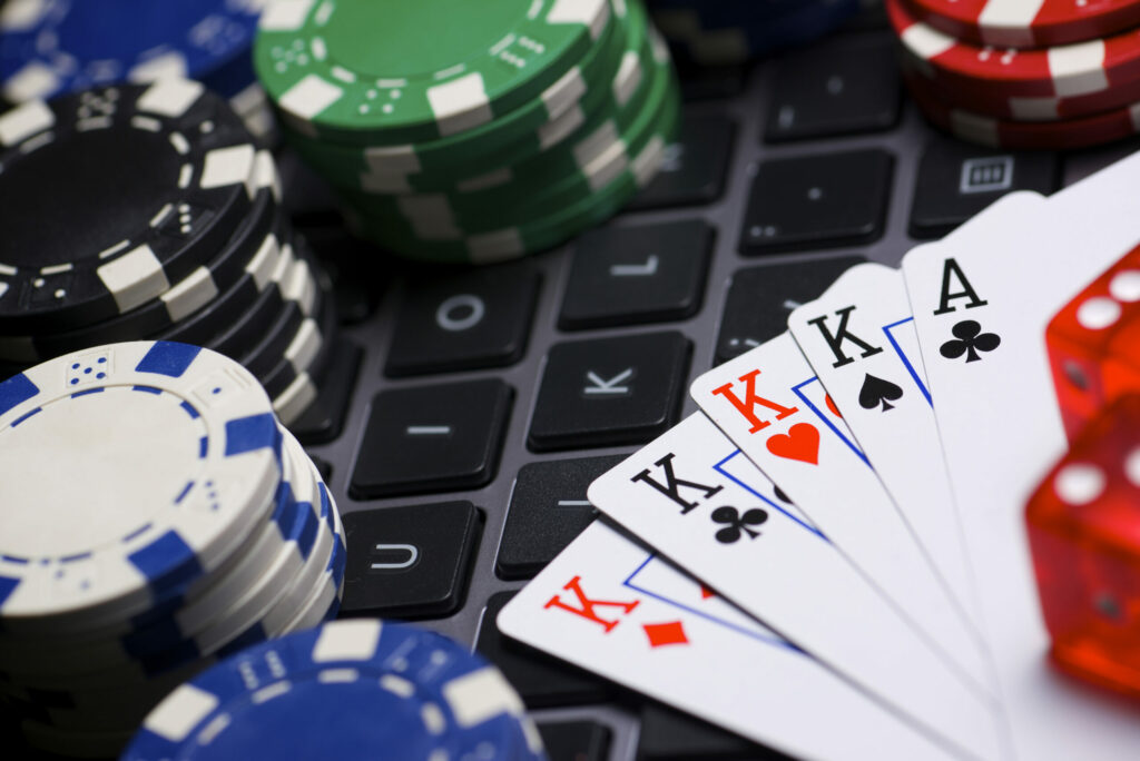 Casino chips, dice and playing cards on a laptop keyboard.