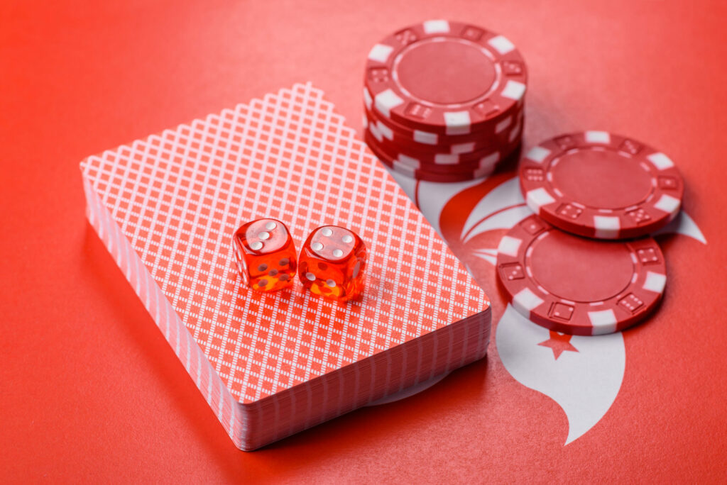 Red dice, red playing cards and red casino chips on a red background.