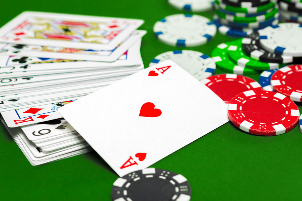 A pile of playing cards and poker chips on a green table.