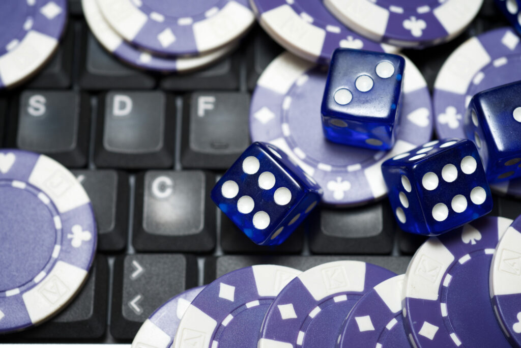 Blue dice and casino chips on top of a black laptop keyboard.