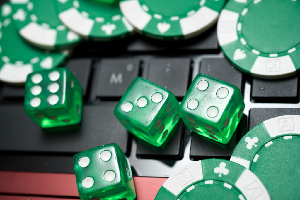 Green casino chips and dice on a laptop keyboard.
