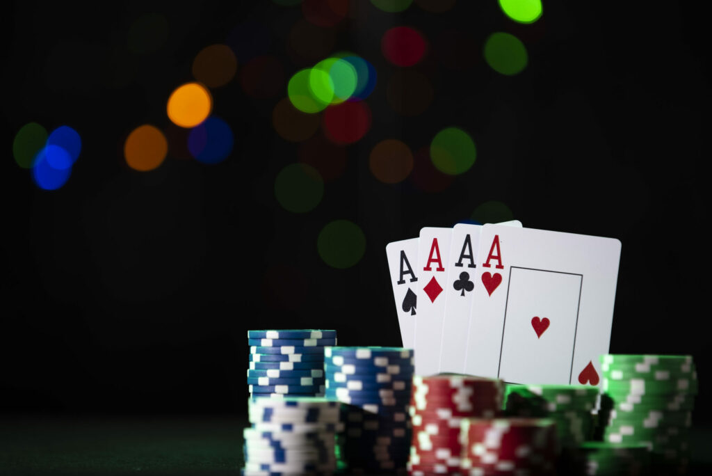 A closeup shot of poker chips and cards on a black bokeh background.