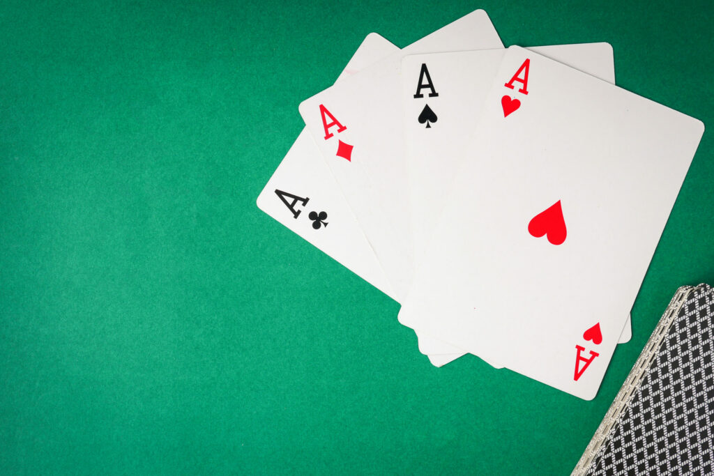 Four Aces on a green background. A deck of cards is in the bottom-right corner.