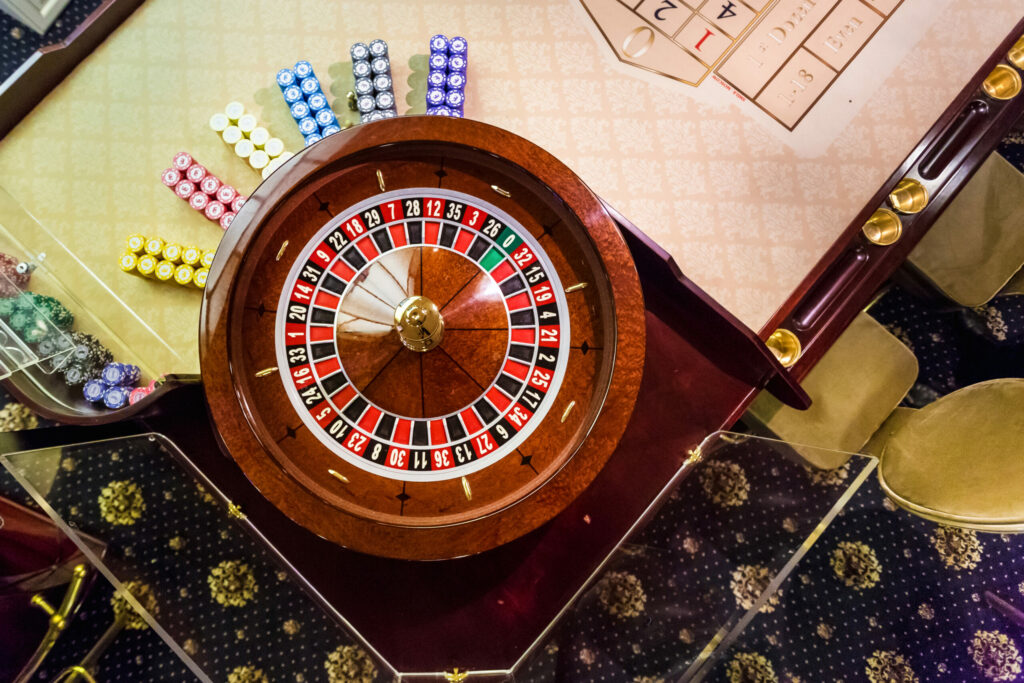 Close up of a roulette wheel on a roulette table in a casino. Beside the wheel are stacks of casino chips.