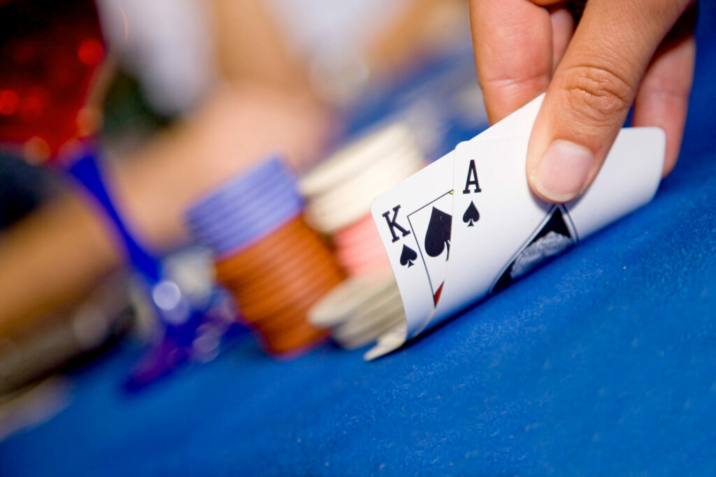Player revealing blackjack hand to themselves. Background is blurred.