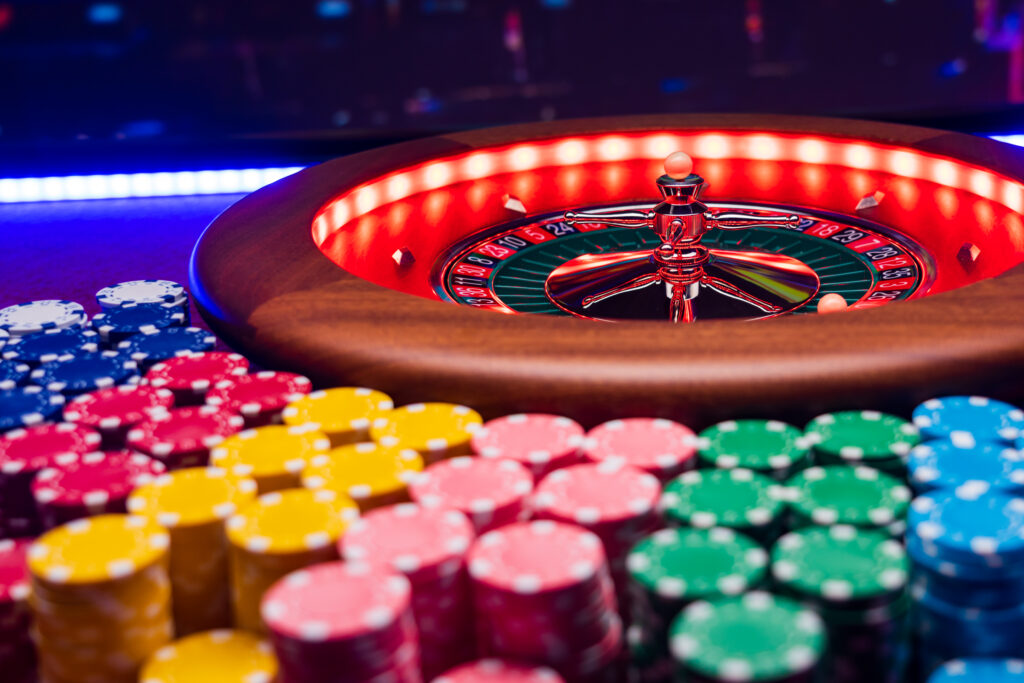 Close up of a roulette wheel surrounded by stacks of casino chips.