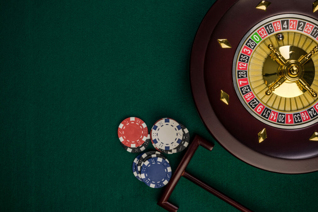 Roulette wheel on a green table along with casino chips.