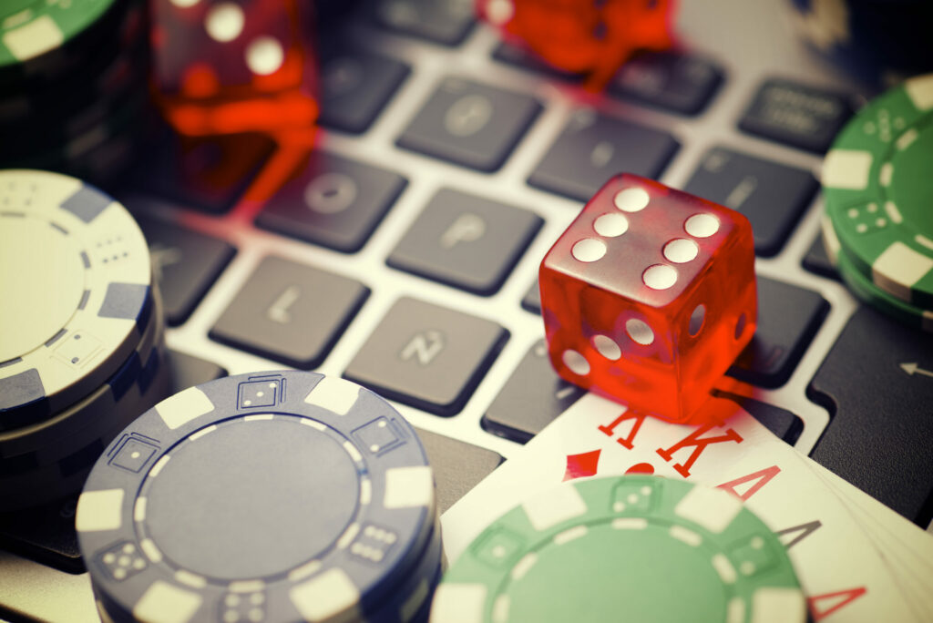 Dice, playing cards and casino chips on a laptop keyboard.