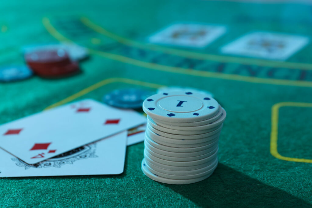 Close up of a blackjack table in a casino with playing cards and casino chips on it.