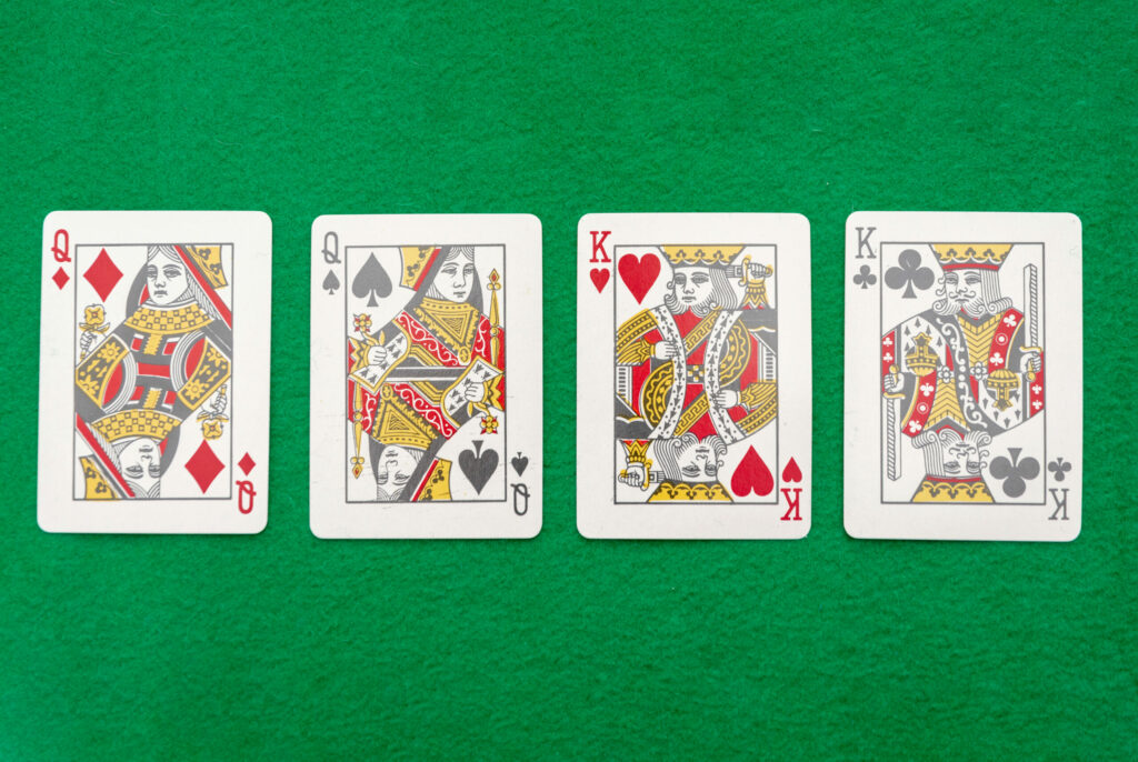 The Queen of Diamonds, the Queen of Spades, the King of Hearts, and the King of Clubs on a green casino table.