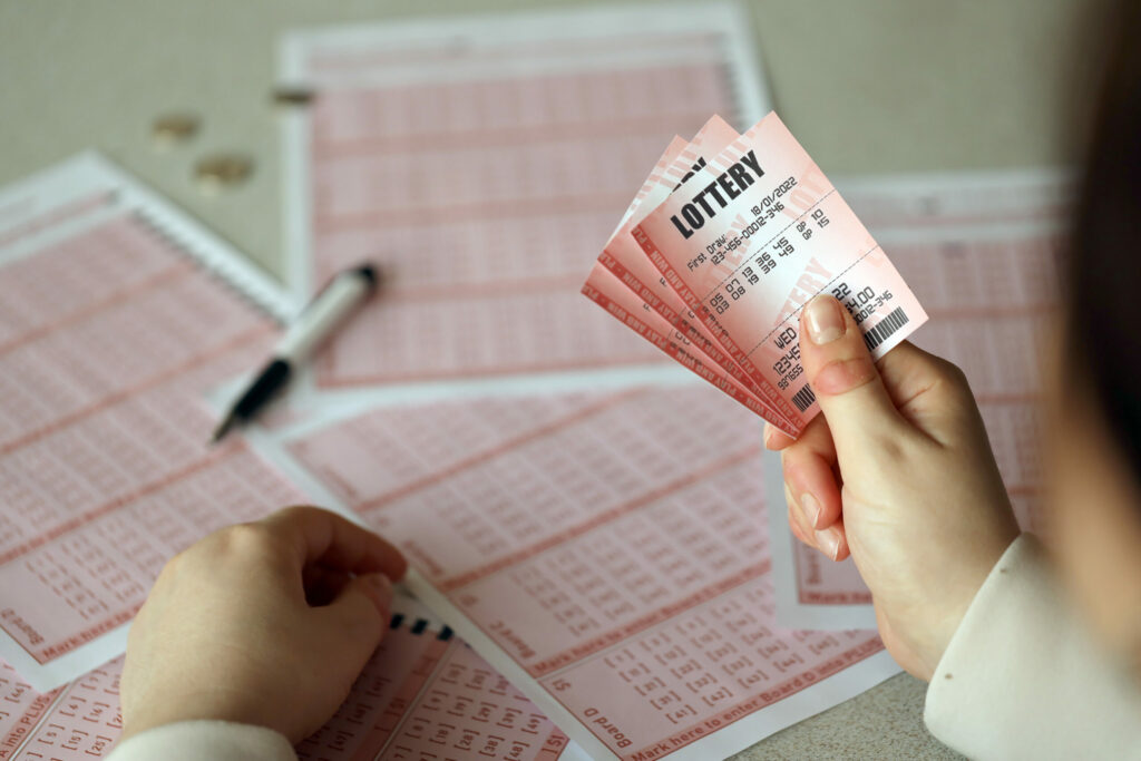 A person, out of frame, hold lottery tickets.