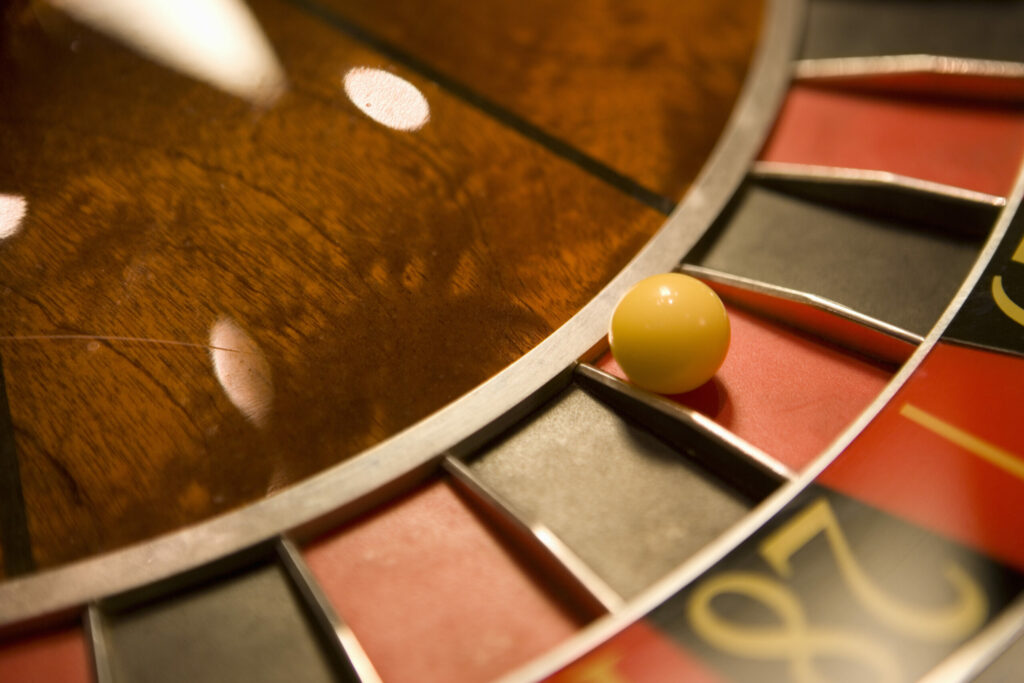 Close up of a roulette ball in a red pocket on a roulette wheel.