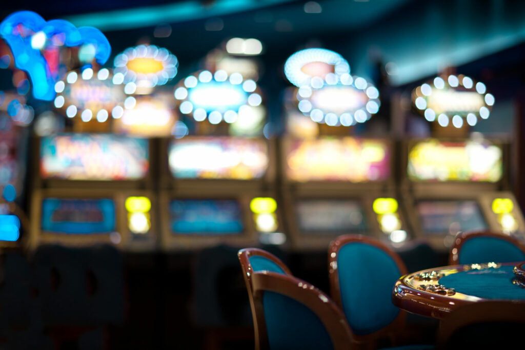 Inside of a casino with a table in focus at the right edge of the image and slot machines blurred in the background.