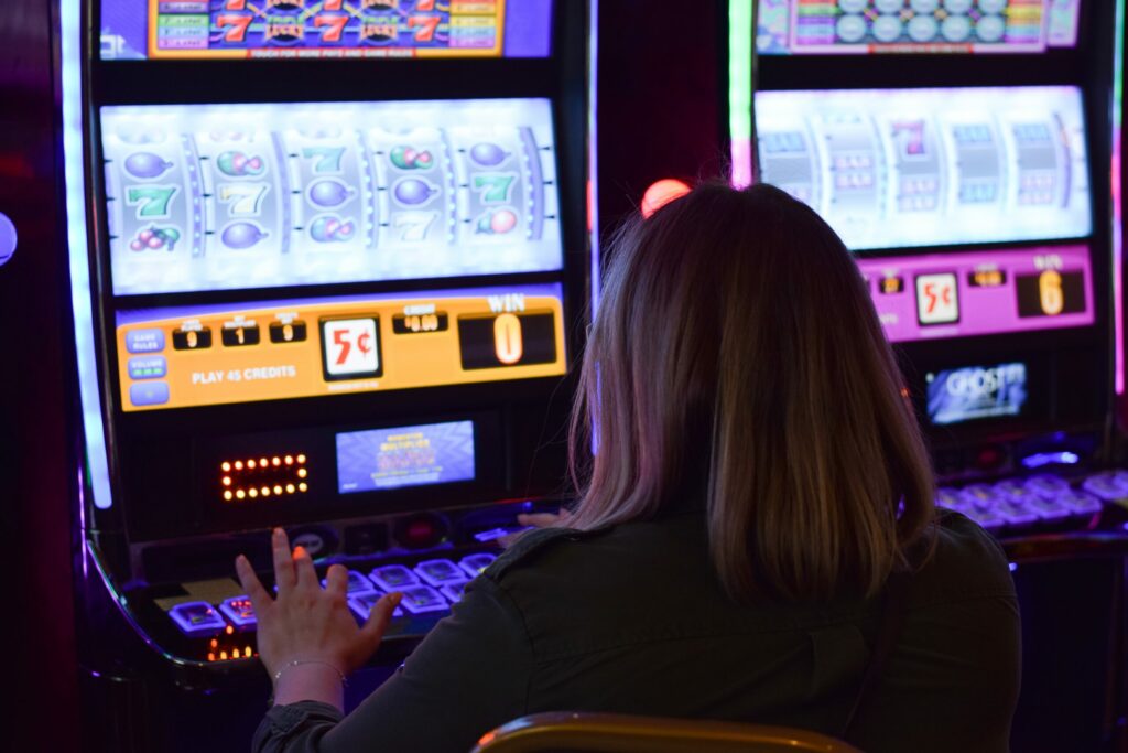 Woman playing at a slot machine with her back to the camera.