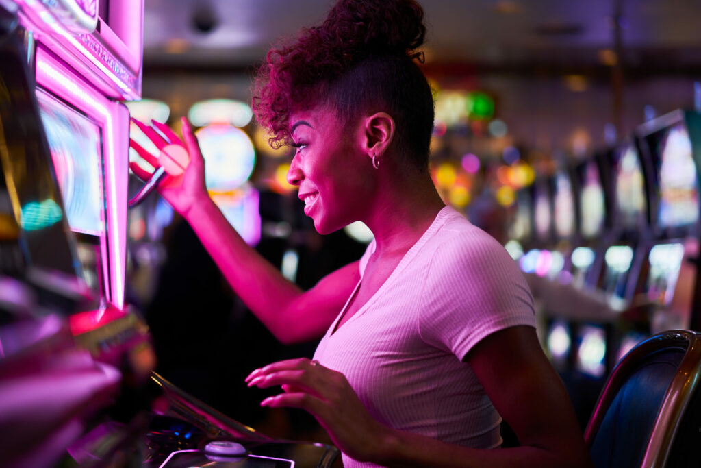 Happy woman playing on a slot machine at a casino.